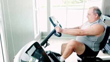 Spor salonunda sabit bir bisiklette çalışan, sağlığını ve sağlıklı bir yaşam tarzını destekleyen kilolu son sınıf öğrencisi. Fitness, kararlılık ve düzenli egzersiz ve kişisel bakım ile iyi yaşlanma.
