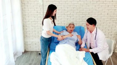 Doktor ve bakıcı hastane yatağında yaşlı bir hastayla konuşuyor. Bir hastane yatak odası, şefkatli sağlık hizmetleri, yaşlı bakımı, iyileşme, iletişim ve tıbbi desteği yansıtıyor..