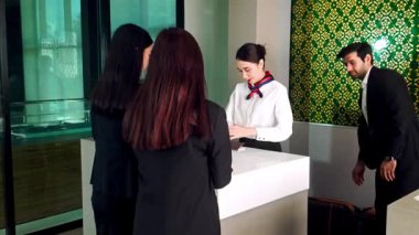 Yolcular, modern bir gişede havayolu personelinin kayıt işlemleri için sırada bekliyorlar. Sahne verimli havaalanı servisi, seyahat hazırlığı ve birinci sınıf müşteri deneyimlerini yakalıyor..