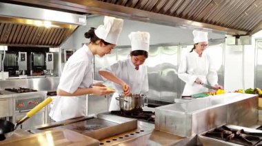 Aşçılık öğrencileri modern bir eğitim mutfağında şefin gözetiminde taze makarna pişirir ve sebze doğrarlar. Aşçılık eğitimi, aşçılık okulları veya yemek hazırlama dersleri için ideal.