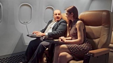 İş adamları uçuş sırasında el sıkışıyorlar, bir uçak kabininde oturuyorlar, başarılı ağ oluşturmayı, şirket seyahatini ve kablosuz ağ bağlantısı ile uçuş içi verimliliği simgeliyorlar..