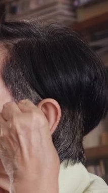 Evde sağduyulu bir işitme cihazı takan yaşlı bir kadının yakın çekimi, işitme kaybı, bağımsız yaşlılar ve sağlık hizmetleri erişilebilirliği çözümleri için modern asistanlık teknolojisini ön plana çıkarıyor..