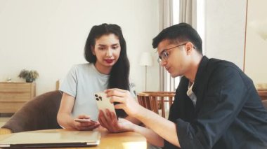 Hintli genç profesyoneller modern bir çalışma alanında akıllı telefonlara bakarken fikirleri tartışıyorlar. Yaratıcı iş konsepti, dijital işbirliği, başlangıç takım çalışması ve mobil strateji planlaması.