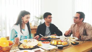 Hint ailesi evde geleneksel yemeklerin tadını çıkarıyor, etnik kıyafetler giyiyorlar. Festival masası etrafında yemek, kültür ve sohbet paylaşımı. Sıcak, özgün bir birliktelik ve kutlama anı..