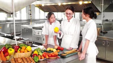 Profesyonel bir aşçılık kursunda taze sebzelerle iki genç aşçılık öğrencisine yemek öğretiyor. Aşçılık eğitimi, gastronomi ve gıda eğitimi konuları için ideal..