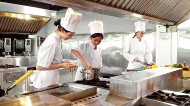 Aşçılık öğrencileri modern bir eğitim mutfağında şefin gözetiminde taze makarna pişirir ve sebze doğrarlar. Aşçılık eğitimi, aşçılık okulları veya yemek hazırlama dersleri için ideal.