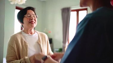 Gülümseyen yaşlı kadın mavi önlüklü bir bakıcı ile sıcak etkileşim içinde, güven, şefkat ve üst düzey sağlık hizmetleri ve günlük yaşam desteği için kaliteli ev sağlığı hizmetlerini sembolize ediyor.