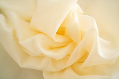 Katları katlanmış yumuşak fildişi şifon kumaş, soyut bir arkaplan oluşturuyor. Tekstil, organza, tül, ipek, saten, kumaş, kumaş ve moda tasarımı için ideal malzeme..