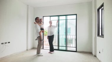 Geniş sürgülü kapıların yakınındaki boş, yeni bitmiş bir dairede çocuklu bir aile, ev satın almayı, teftişi veya taşınmayı öneriyor..