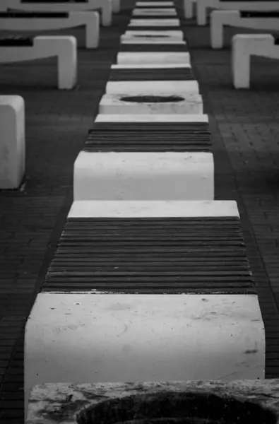 形成一排均匀的城市背景的混凝土长椅的黑白照片 — 图库照片
