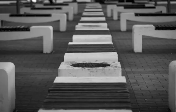 コンクリートのベンチの白黒写真は 偶数行の都市の背景を形成しました — ストック写真