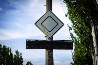 Renkli yatay fotoğraf, yol kenarı tabelaları, silahlı saldırganlıkla bağlantılı sokak isimleri, şehir manzarası aşağıdan yukarıya, tepeden tırnağa..