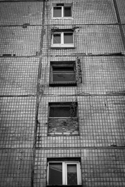 Tek renkli dikey fotoğraf, kahverengi kiremitlerden oluşan ön cephesi olan eski konut binası, yukarıdaki pencereler, aşağıdan yukarıya doğru odaklanmış..