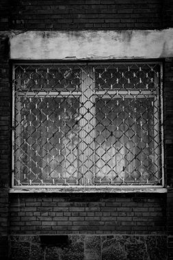 Tek renkli dikey fotoğraf, eski camlarında metal parmaklık olan tuğla kırmızı bina ve ahşap çerçeveler, şehir arka planı.. 