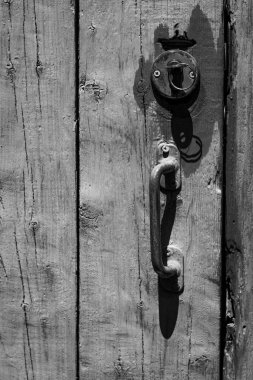 Paslı kilidi ve kapı kolu olan eski ahşap bir kapının dikey yakın çekimi. Arkaplan ve dokular.