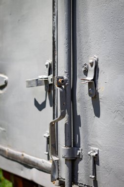 Metal yüzey desenli, çeşitli bileşenleri, cıvataları ve menteşeleri olan mandal mekanizması görünür, engebeli endüstriyel tasarımı vurguluyor..