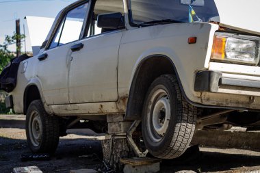 Araba kaldırılmış ve kalaslarla desteklenmiş. Araba tamiri, kriko kaldırma.