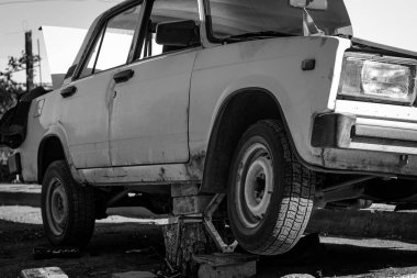 Araba kaldırılmış ve kalaslarla desteklenmiş. Araba tamiri, kriko kaldırma.