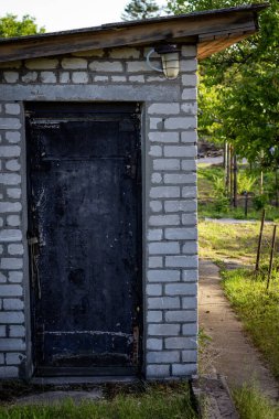 Bahçenin arka bahçesindeki eski tuğladan bir ahırın siyah giriş kapısı. Güneşli bir gün