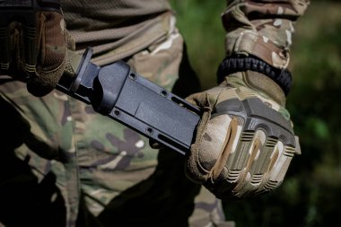 Telsizli bir asker, iç çamaşırına takılı bir bıçaktan askeri bir bıçak çıkardı. Askeri teçhizat, askeri işler..