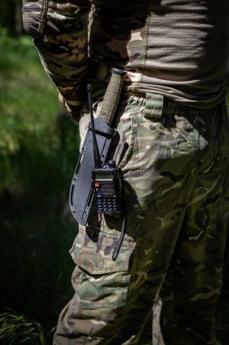 Askeri bıçak ve telsiz üniformalı bir askerin kemerinde asılı. Askeri teçhizat, taktik teçhizat, savaş ekipmanı.