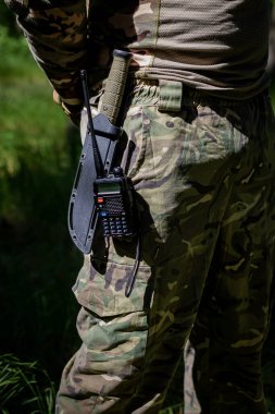 Askeri bıçak ve telsiz üniformalı bir askerin kemerinde asılı. Askeri teçhizat, taktik teçhizat, savaş ekipmanı.