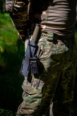 Askeri bıçak ve telsiz üniformalı bir askerin kemerinde asılı. Askeri teçhizat, taktik teçhizat, savaş ekipmanı.