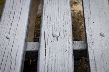 Horizontal color photo, wooden cracked slats connected by metal fasteners close together on gray concrete background. clipart