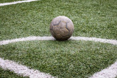Yeşil bir futbol sahasına yakın eski kirli bir topun renkli yatay fotoğrafı. Takım sporu, stadyumda futbol maçı..