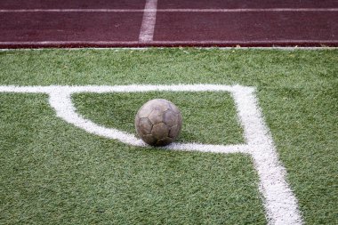 Renkli yatay fotoğraf, yeşil çimlerde eski futbol topu ve beyaz çizgi, stadyumda aktif spor. 
