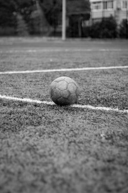 Siyah ve beyaz dikey fotoğraf, yeşil çimlerde ve beyaz çizgide eski futbol topu, stadyumda aktif spor.