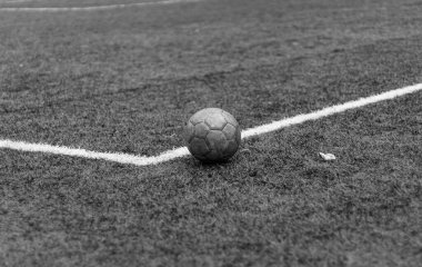 Siyah ve beyaz yatay fotoğraf, yeşil çimlerde ve beyaz çizgide eski futbol topu, stadyumda aktif spor.
