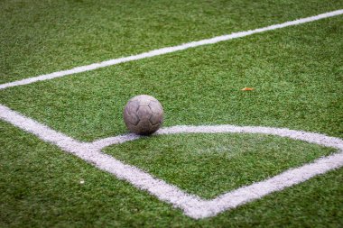 Renkli yatay fotoğraf, yeşil çimlerde eski futbol topu ve beyaz çizgi, stadyumda aktif spor. 