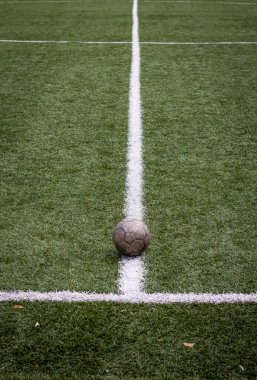 Renkli dikey fotoğraf, yeşil çimenli ve beyaz çizgili eski futbol topu, stadyumda aktif spor.