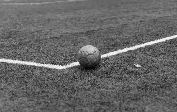 Siyah ve beyaz yatay fotoğraf, yeşil çimlerde ve beyaz çizgide eski futbol topu, stadyumda aktif spor.
