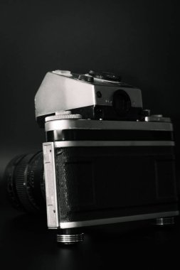 Engebeli, siyah deri dış ve krom aksanlı klasik bir kamera. Kamera elle kapatma mekanizmasına sahip.