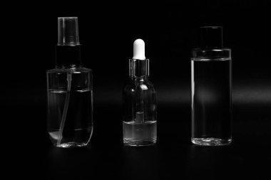 Sıvı dolu üç kozmetik şişe: solda şeffaf silindirik gövdeli bir sprey şişesi var, ortada da bir damla şişesi. Sağda vida kapaklı bir şişe var..