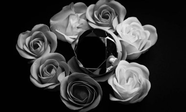 Sabun gülleri, arka planda yansıtıcı mücevhere benzer bir nesnenin etrafına dizilmiş. Yapraklar zarif bir şekilde işlenmiş, çeşitli renkler sergiliyor..