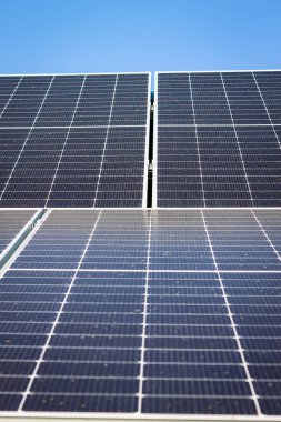Izgara desenli güneş panelleri, görüntüyü gökyüzüne doğru bir açıyla doldurur. Paneller karanlık ve güneş enerjisini yakalayan daha aydınlık çizgiler var. Bu temiz enerji teknolojisi.
