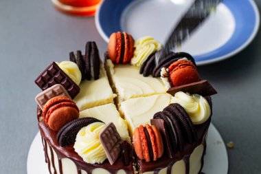 Kek, şekerli ve kenarları koyu çikolatalı. Pasta çikolata, turuncu badem kurabiyesi ve kremalı buklelerle süslenmiş. Bıçak pastayı keser, ortası çok katmanlıdır..