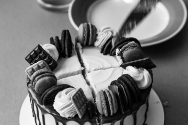 Kek, şekerli ve kenarları koyu çikolatalı. Pasta çikolata, turuncu badem kurabiyesi ve kremalı buklelerle süslenmiş. Bıçak pastayı keser, ortası çok katmanlıdır..