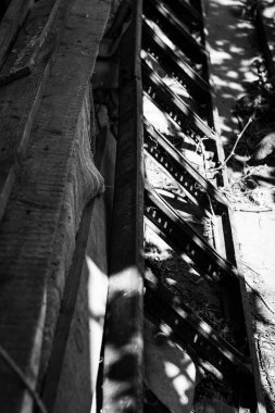 Paslı metal basamaklar beton ya da taş kenarlara paralel gidiyor. Metal bileşenler, gözle görülür pas ve birikmiş enkaz ve ihmal belirtileri gösteriyor..