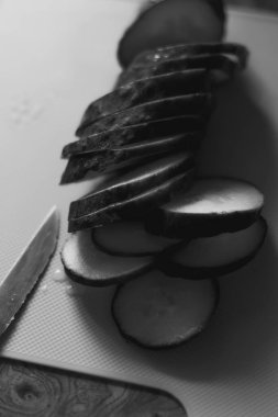 Salatalık dilimleri bir bıçağın yanındaki tahta üzerinde düzenlenir. Salatalık koyu yeşil, taze ve çıtır çıtır ve bıçağın metal bir bıçağı var..