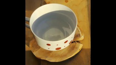 Tahta tepside duran cam bir çaydanlıktan fincana kahve dolduran bir kadının yakın çekimi..