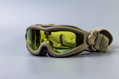 Haki çerçeveli tek bir taktik askeri gözlük ve tarafsız bir arkaplanda sarı-yeşil lens. Saha operasyonları için temel göz koruması. 2 Ekim 2025, Kamianske, Ukrayna.