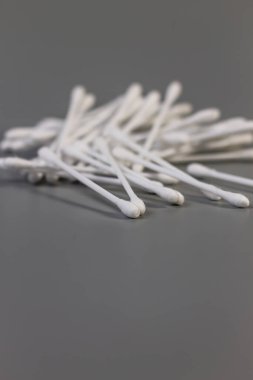 Son derece sığ bir alan derinliğine sahip beyaz pamuklu çubukların dikey düşük açılı görüntüsü arka planı bulanıklaştırıyor ve pamuğun yumuşak dokusunu vurguluyor..