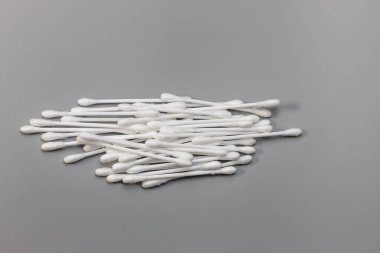 Gri bir stüdyonun arka planında duran beyaz pamuklu çubuklar (kulak çubukları). Hijyen ve kişisel bakım kavramı.