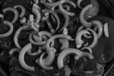 Tek renkli çiğ domuz bifteği bol bol taze tatlı soğan halkalarıyla kaplıdır. Lezzetli bir pişirme işleminden önce bir sıvıda marine edilir..