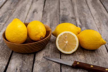 Eski ahşap bir masada mutfak bıçağıyla bir grup taze limon. Seçici odak.