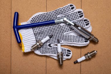 Bujiler, buji anahtarı ve tahta masada koruyucu eldivenler..